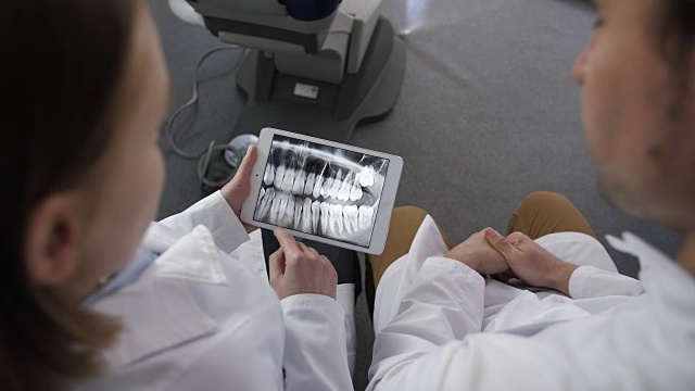 上角度的牙医在触摸板上看x光片视频素材