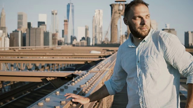 快乐的游客倚靠在布鲁克林大桥的铁轨上，欣赏着壮观的纽约市建筑全景4K视频素材