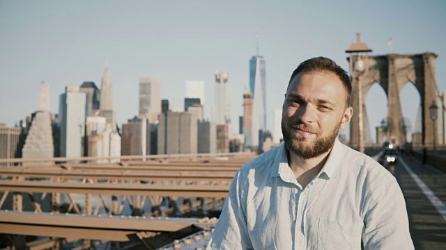 在纽约市布鲁克林大桥上，成功的白人商人双臂交叉，对着镜头微笑视频素材