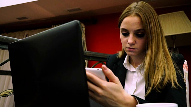 在餐馆里拿着智能手机和笔记本电脑的年轻女孩视频素材
