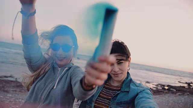 年轻的潮女们在海滩上用五颜六色的烟雾弹庆祝视频素材