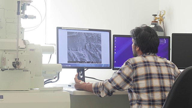 年轻研究员在电脑显示器上分析科学样本视频素材