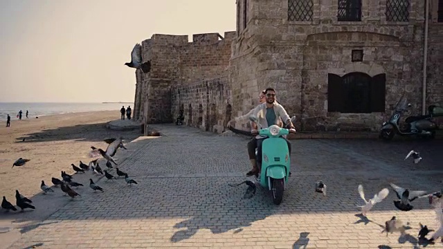 年轻的游客夫妇在古老的欧洲城市骑摩托车视频素材