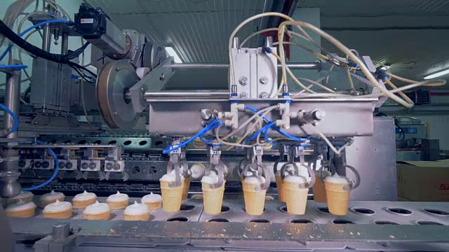 华夫饼冰淇淋杯正在从传送带转移到一个旋转的机器视频素材