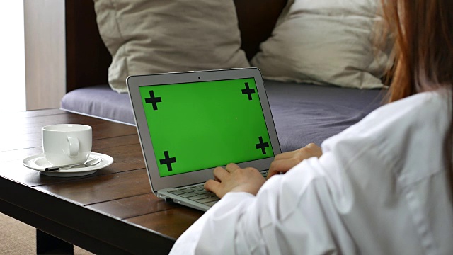 年轻女子使用绿屏笔记本电脑视频素材