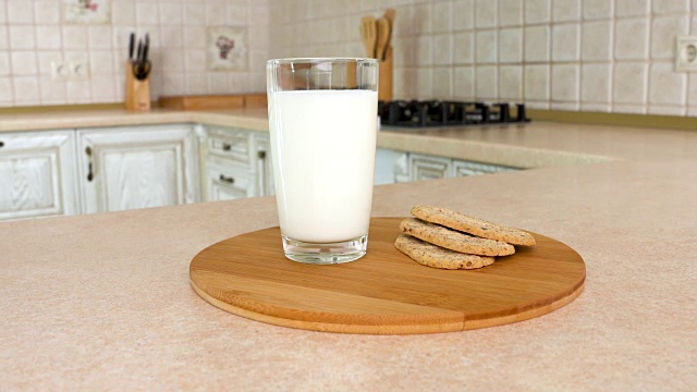 特写是一杯牛奶和健康脆脆的早餐饼干。以白色厨房为背景的旋转相机。Dolly-shot。视频素材