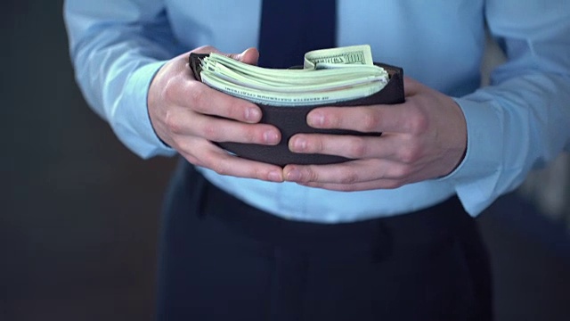男人把一大捆钞票塞进钱包，货币贬值，通货膨胀视频素材