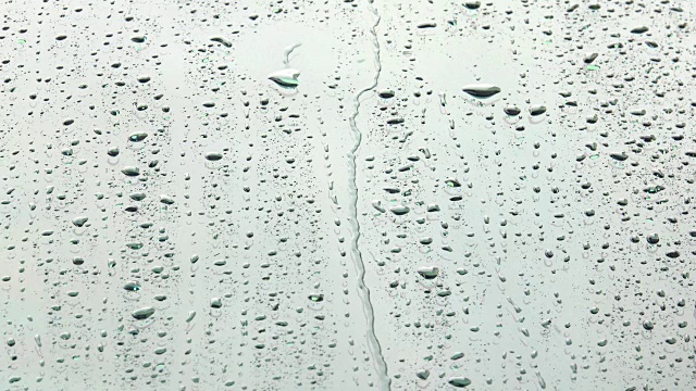 阳光下的雨点或水滴在玻璃上流动。特写雨落溅在明亮的表面的镜子的汽车背景视频素材