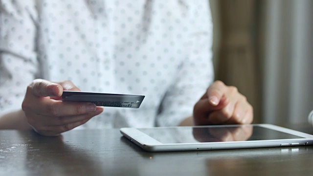 手里拿着信用卡的女人用平板电脑在网上购物视频素材