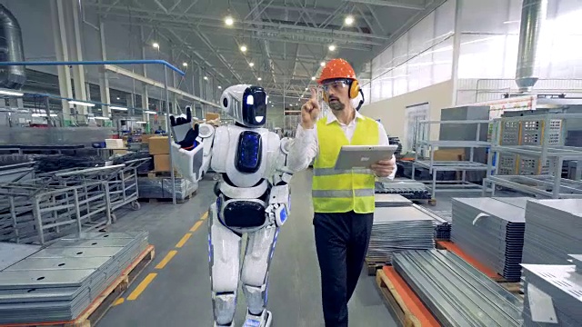 人类工厂工人和机器人一起在工厂里行走视频下载