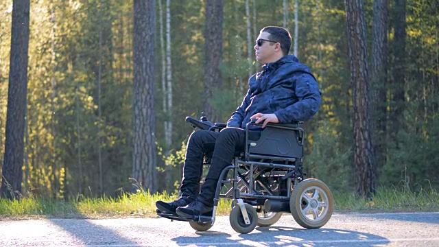 一个坐在轮椅上的人在森林里环顾四周。视频下载