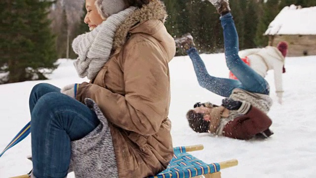 SLO MO夫妇骑着雪撬，笑着掉了下来视频素材