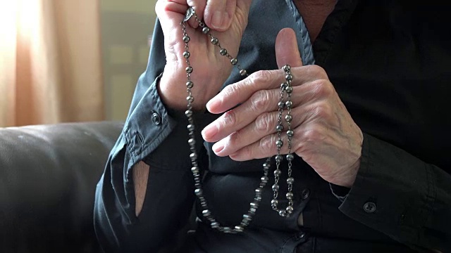 天主教:一位年长妇女手持念珠祈祷视频下载