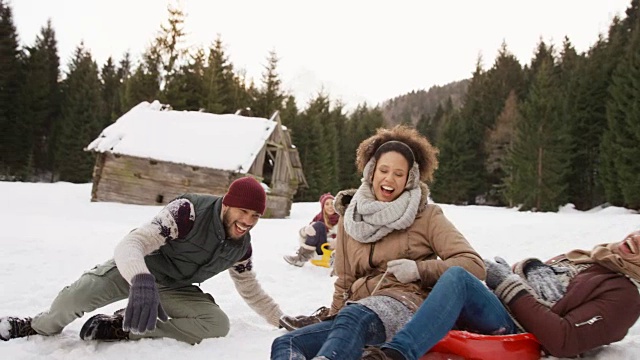 一群从雪橇上摔下来的年轻人在雪地里大笑视频素材