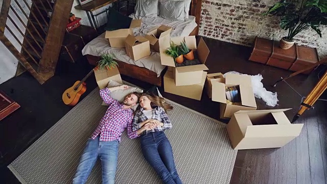 俯视图有吸引力的丈夫和妻子躺在新房子的卧室地板上聊天。年轻的家庭，关系和搬迁概念。视频素材