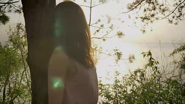 年轻美丽的姜黄色女孩站在海滩上的树，自然，剪影50 fps视频素材