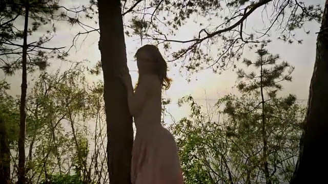 年轻美丽的姜黄色微笑女孩在海滩上的森林，站在树，自然，剪影，看着50帧/秒视频素材