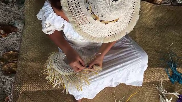 库克群岛拉罗汤加，一名太平洋岛民戴着里托帽，正在编织一把手扇子视频下载