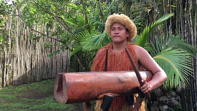 在拉罗汤加库克群岛，一名太平洋岛民在一种巨大的圆木Pate鼓乐器上演奏音乐视频下载