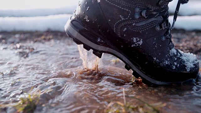 徒步者穿着靴子在冬天的道路上溅水，超级慢的动作视频下载
