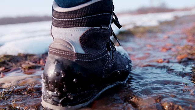 徒步者穿着靴子走在雪地里的水里，超级慢动作视频下载