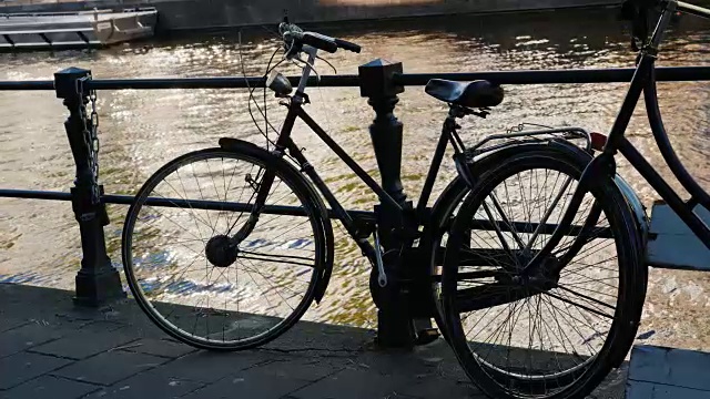 这辆自行车停在阿姆斯特丹运河的栏杆旁。一个典型的城市生活场景。自行车是阿姆斯特丹的标志之一视频素材