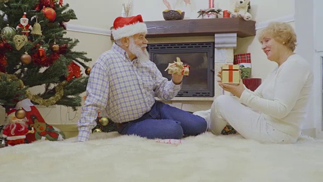 老人和老人躺在毛茸茸的地毯上交换圣诞礼物视频素材