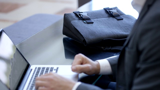 一个拿着公文包在酒店大厅的笔记本电脑上打字的商人视频下载