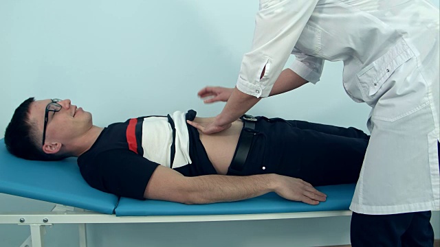 女医生正在检查躺在医院沙发上的男病人的腹部视频下载