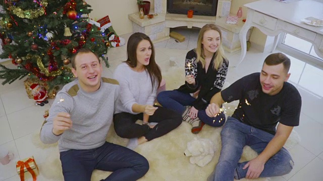四个朋友拿着烟花坐在地板上庆祝圣诞节视频素材