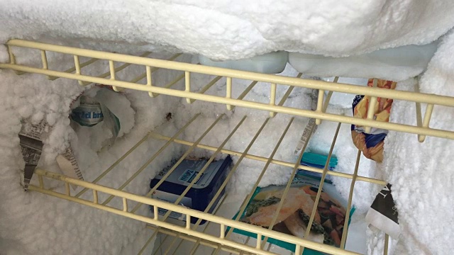 有冰的旧冰箱和食物需要解冻。视频素材