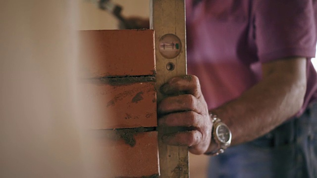 一个泥瓦匠正在工作。特写镜头显示，一名男子正在赤手空拳地在水泥溶液上砌砖视频素材