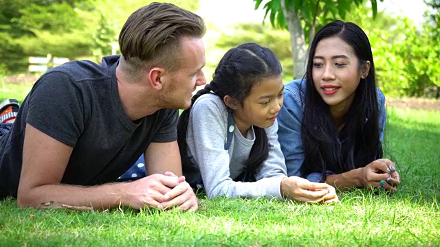 亚洲爸爸和妈妈在公园里读故事书视频素材
