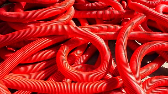 工业背景。塑料波纹管，排水中卷，特写。红色的管子或管道。慢动作视频下载