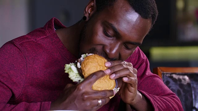 胖胖的非裔美国人在吃汉堡。视频下载