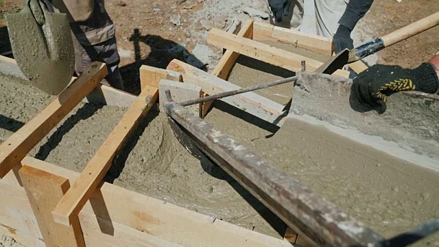 用混凝土建造小房子。液体混凝土灌注到木模板中，形成建筑物的基础视频素材
