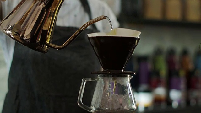 可爱的日本咖啡师将热水倒在磨碎的咖啡豆上视频素材