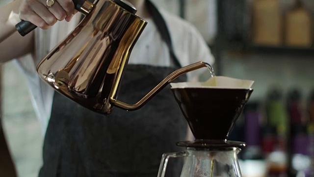 可爱的日本咖啡师将热水倒在磨碎的咖啡豆上(慢镜头)视频素材