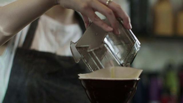 可爱的日本咖啡师倒磨碎的咖啡豆(慢镜头)视频素材