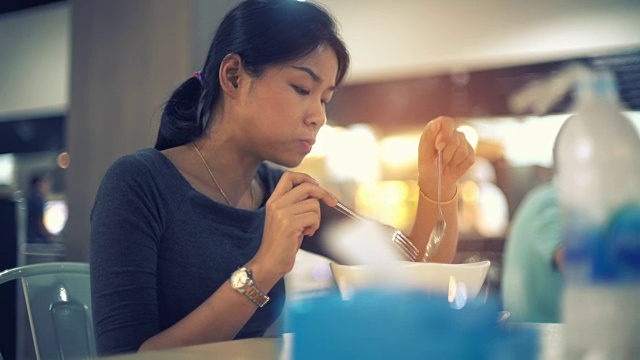 年轻的亚洲女士吃面汤在美食广场色调的视频视频素材