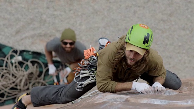 当保护者从下面向上看时，攀岩者伸出手抓住陡峭的岩壁并站稳脚跟。视频素材