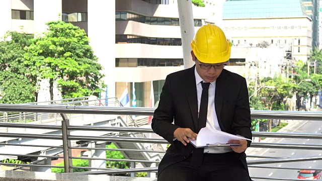 穿着正装的亚洲年轻工程师读一份新项目的报告视频素材