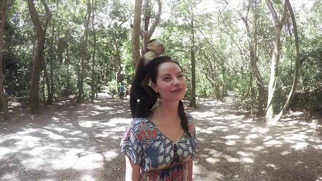 一个女人把一只猴子顶在头上。视频素材