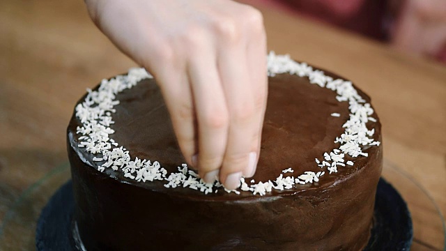用椰子屑装饰巧克力椰子蛋糕。视频素材