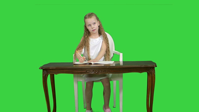 可爱的小女孩在做作业，在绿屏上写字，色度键视频下载