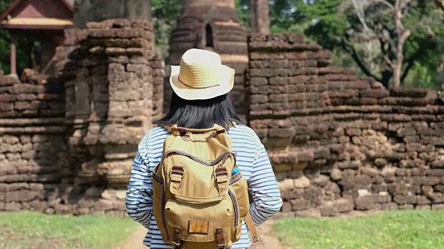 亚洲旅行者女人行走在古老的塔寺庙泰国建筑在素可泰，泰国。女性游客游览城市的概念。视频下载