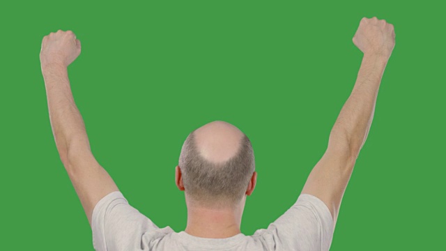 成功的秃头男人举起双手在绿色键盘上庆祝。阿尔法通道视频下载