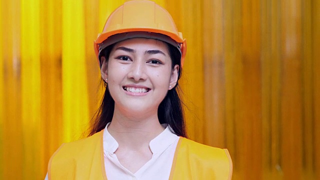 一个美丽的女人的肖像微笑的女工程师走向相机在工厂视频素材