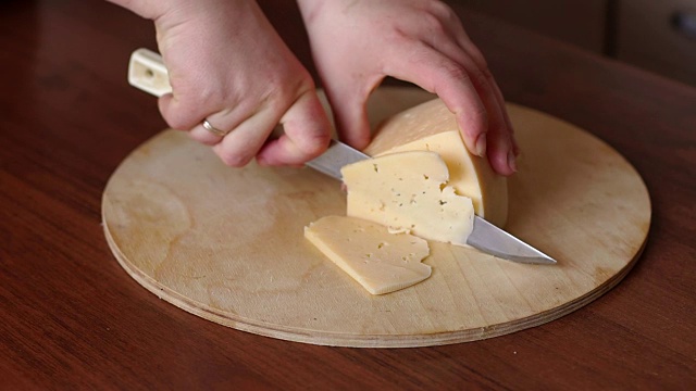 女孩在砧板上切奶酪，特写。视频素材