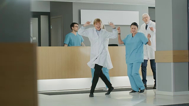 医生、护士和助理在手术成功后跳舞，他们走过现代医院的大厅。医务人员在玩视频素材